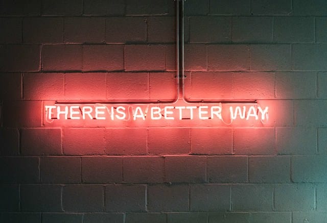 Red neon sign reading "THERE IS A BETTER WAY" mounted on a brick wall
